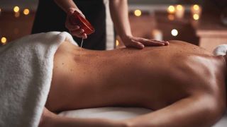 personne réalisant un massage aux huiles essentielles apaissantes sur le dos d'une femme